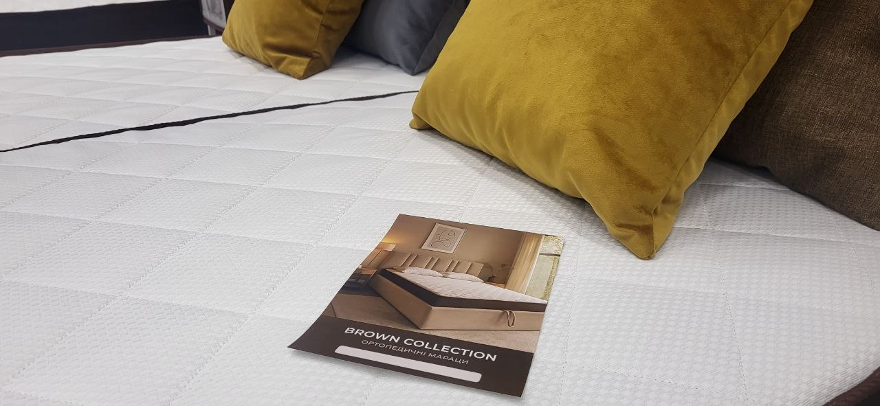 Крупний план матраца з буклетом Brown Collection та декоративними подушками